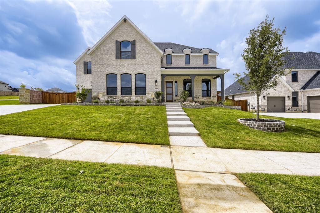 794 White Sage Road, Haslet, TX 76052 Light-colored brick exterior featuring a covered porch with dark columns, arched windows, and dark shutters