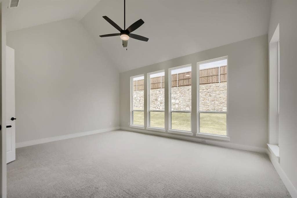 794 White Sage Road, Haslet, TX 76052 Room featuring a vaulted ceiling with a ceiling fan, light-colored carpeting, and a series of four tall windows
