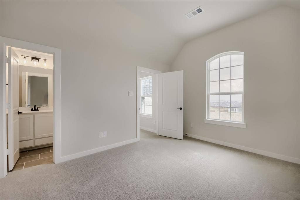 794 White Sage Road, Haslet, TX 76052 Carpeted room featuring a vaulted ceiling and an arched window with grid detailing