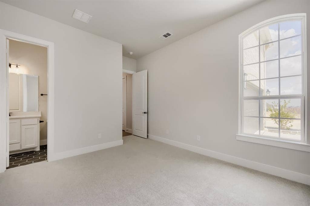 794 White Sage Road, Haslet, TX 76052 Arched window with gridded panes, light gray wall paint, white baseboards, and neutral carpeting