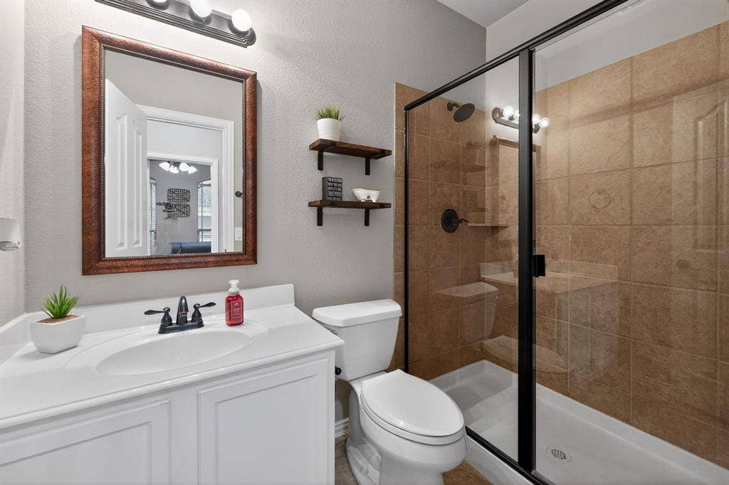 2760 Explorador, Grand Prairie, TX 75054 Downstairs Bathroom featuring a shower with glass enclosure and brown tile surround