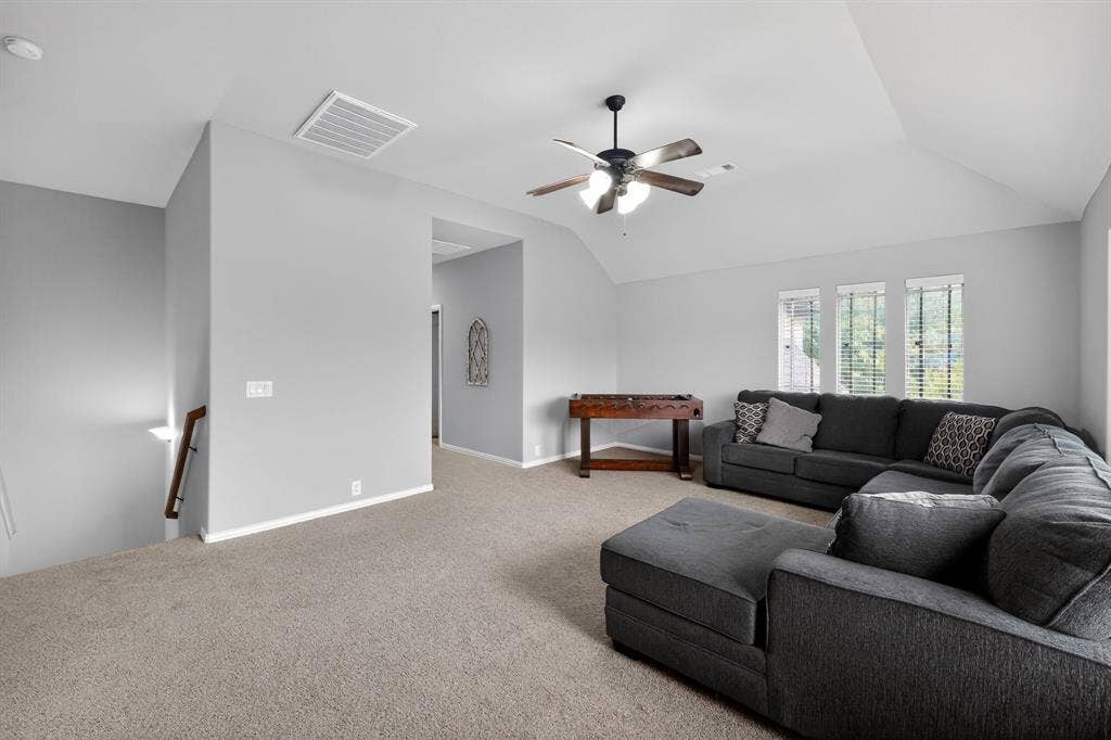 2760 Explorador, Grand Prairie, TX 75054 Upstairs spacious entertainment room featuring carpet, vaulted ceilings, a ceiling fan with light fixture, and triple windows with blinds