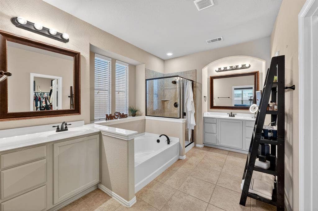 2760 Explorador, Grand Prairie, TX 75054 Spacious bathroom featuring dual vanities with integrated sinks, a built-in soaking tub, and a separate glass-enclosed shower