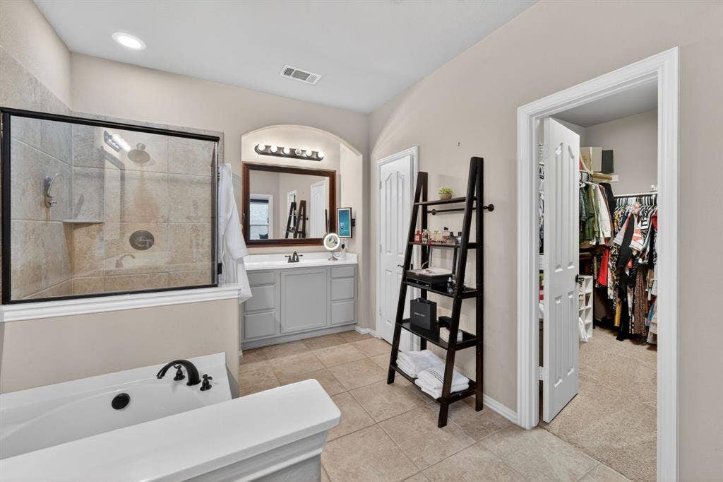 2760 Explorador, Grand Prairie, TX 75054 Bathroom featuring a tiled shower with a black frame enclosure, a separate soaking tub with black fixtures, and a vanity with a single sink and wall-mounted lighting