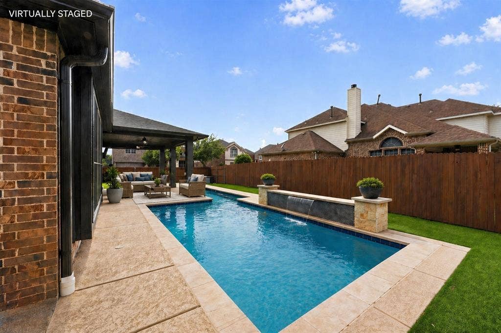 2760 Explorador, Grand Prairie, TX 75054 Backyard oasis featuring a rectangular swimming pool with integrated water features, stone accents, covered patio area and artificial turf