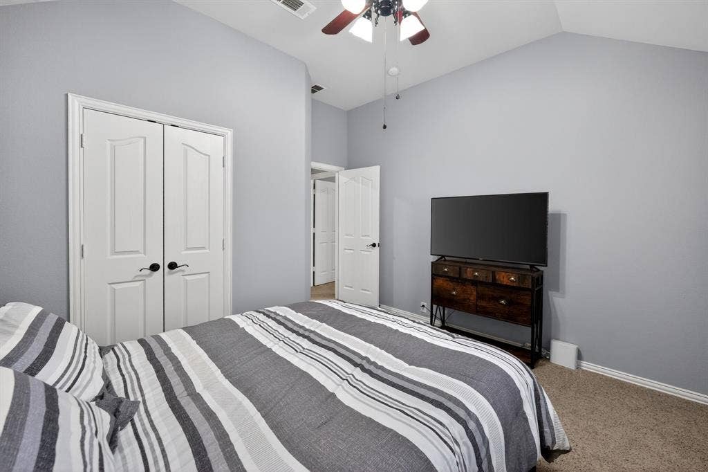 2760 Explorador, Grand Prairie, TX 75054 Upstairs - Bedroom # 3 - featuring vaulted ceiling with a ceiling fan, light gray wall paint, white trim, carpet flooring and double door closet