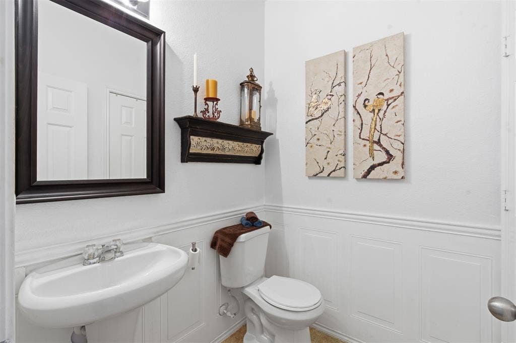 1081 Barrington Drive, Prosper, TX 75078 Pedestal sink with chrome-finish faucet, framed mirror, and wainscoting