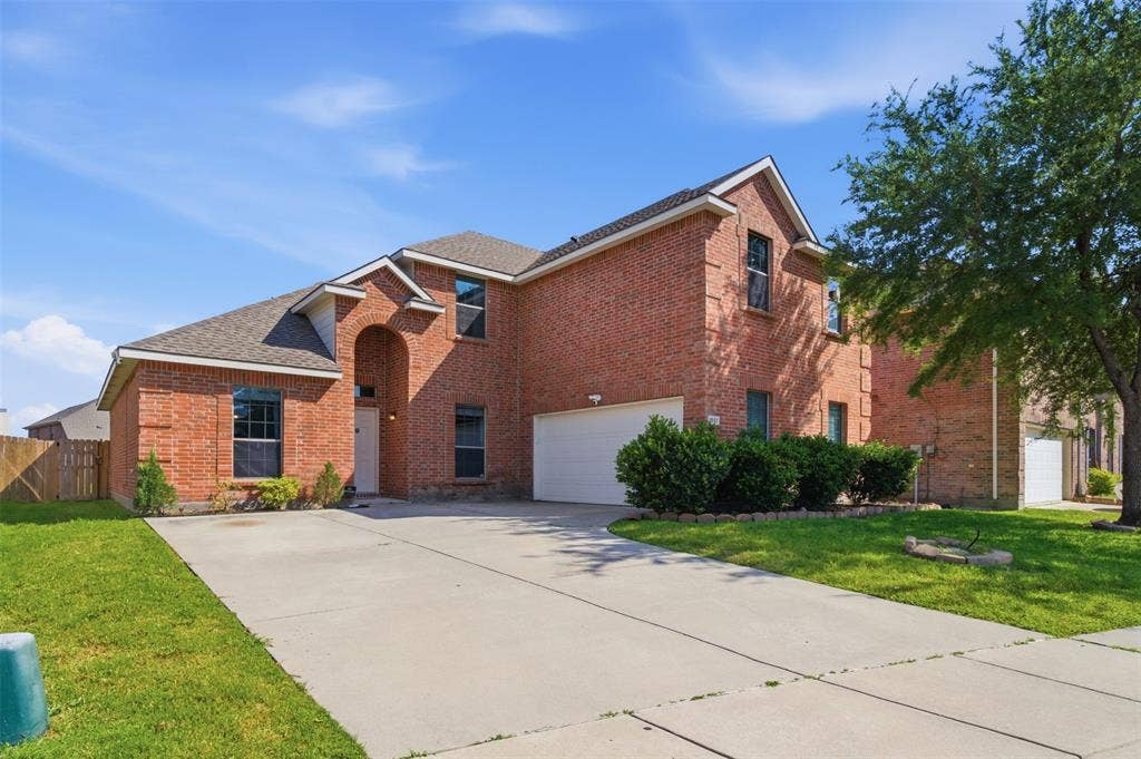 1081 Barrington Drive, Prosper, TX 75078 Two-story brick exterior featuring an arched entry, an attached two-car garage, multiple windows, and a concrete driveway