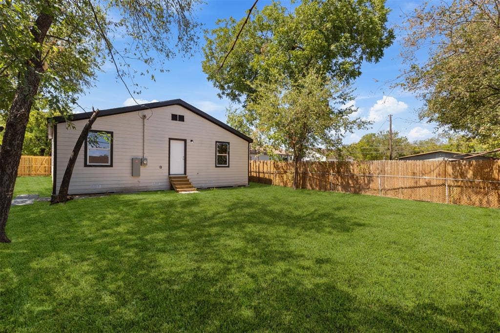 314 NW 15th Street, Grand Prairie, TX 75050 Expansive backyard with a manicured lawn, full perimeter wood fencing, and mature trees