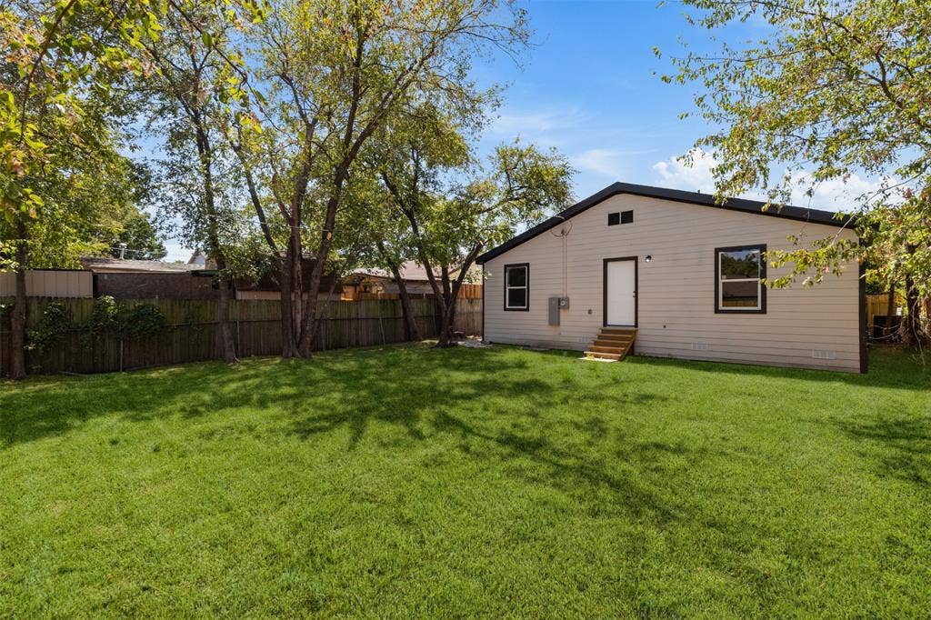 314 NW 15th Street, Grand Prairie, TX 75050 Expansive backyard featuring a lush lawn, mature trees, and a wood privacy fence