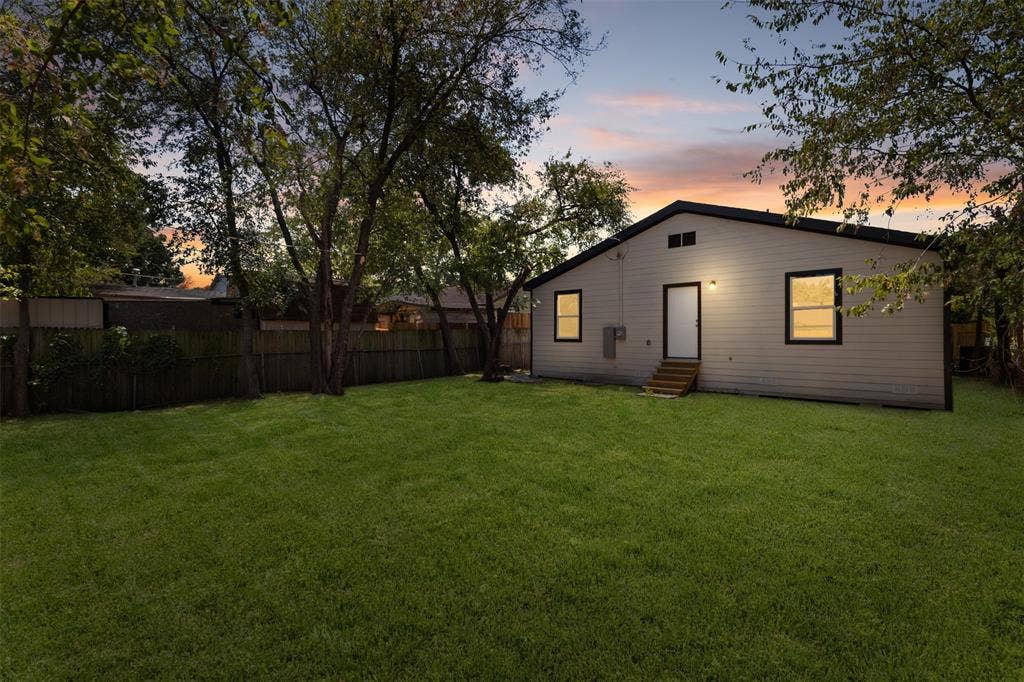 314 NW 15th Street, Grand Prairie, TX 75050 Expansive green lawn with mature trees and a wood privacy fence
