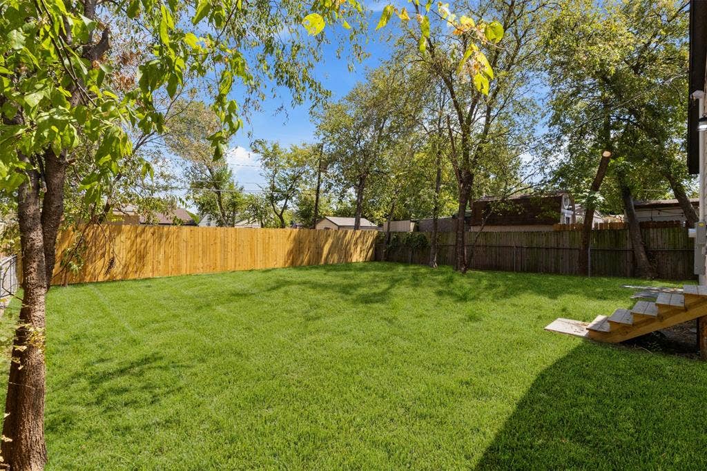 314 NW 15th Street, Grand Prairie, TX 75050 Expansive backyard with a manicured lawn, established trees, and a privacy fence
