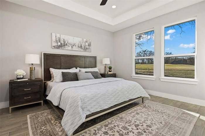 203 Saint Andrews Drive, Mabank, TX 75156 Spacious bedroom featuring two large windows, a tray ceiling, and wood-finish flooring