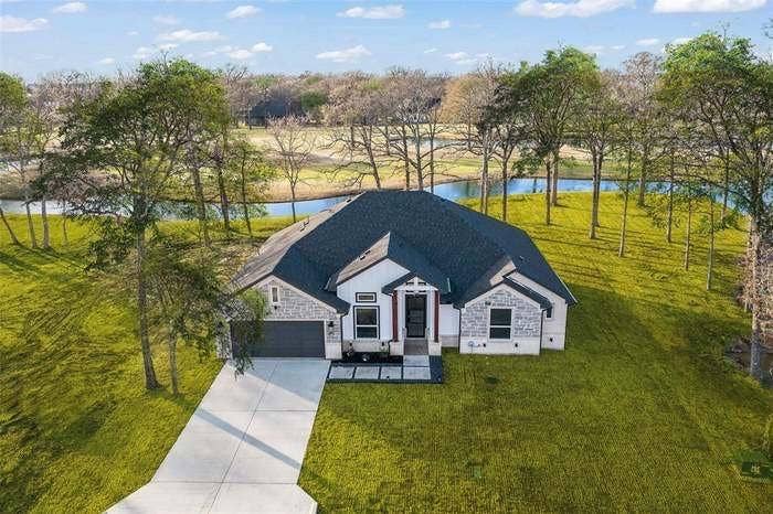 203 Saint Andrews Drive, Mabank, TX 75156 Contemporary residence featuring a dark shingle roof, stone and siding exterior, an attached garage, and a concrete driveway