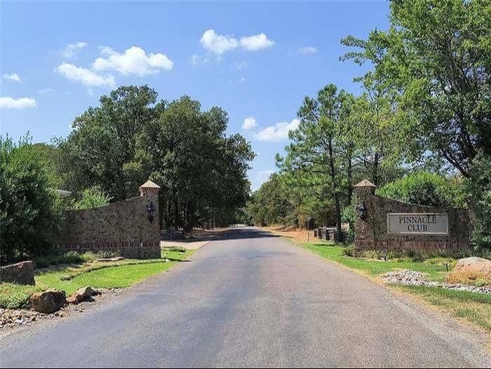 203 Saint Andrews Drive, Mabank, TX 75156 Stone entrance feature with "Pinnacle Club" signage, flanked by established trees and a paved roadway