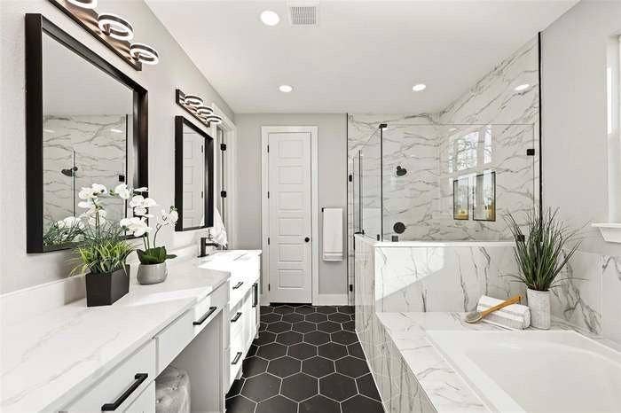 203 Saint Andrews Drive, Mabank, TX 75156 Spacious bathroom featuring a glass-enclosed shower, built-in bathtub, dual vanity with white countertops, black hexagonal floor tiling, and marble-patterned wall finishes