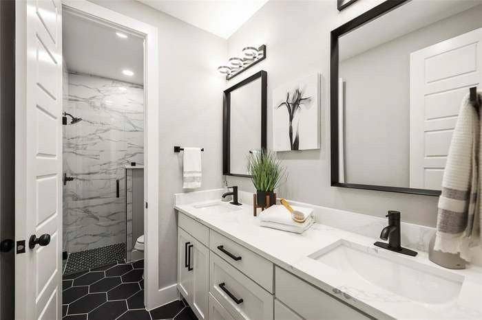 203 Saint Andrews Drive, Mabank, TX 75156 Contemporary bathroom featuring a double vanity with white cabinetry and integrated sinks, matte black hardware, and an overhead decorative light fixture