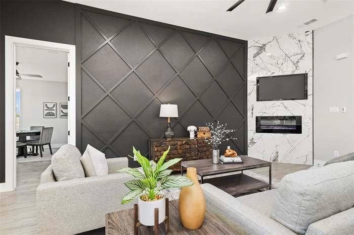 203 Saint Andrews Drive, Mabank, TX 75156 Living area featuring a geometric accent wall, a fireplace with a stone surround, and wood-finish flooring