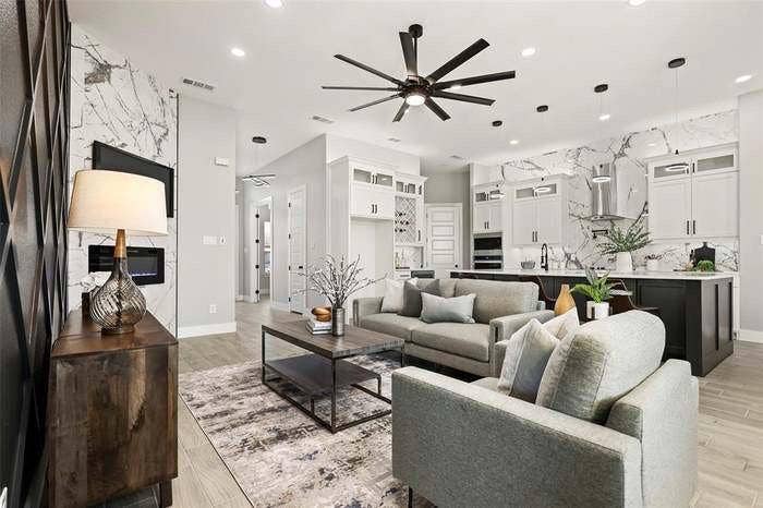 203 Saint Andrews Drive, Mabank, TX 75156 Open-concept living space featuring a modern kitchen with a large island and full-height backsplash, a spacious living area with a ceiling fan, a fireplace with a stone surround, recessed lighting, and wood-finish flooring