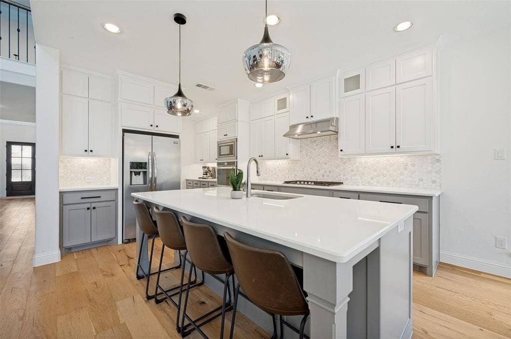 961 Gladewater Drive, Prosper, TX 75078 This bright kitchen is equipped with everything you need! From white counter tops and neutral cabinets with oversized island and stainless steel appliances, it is a room both functionally and visually appealing