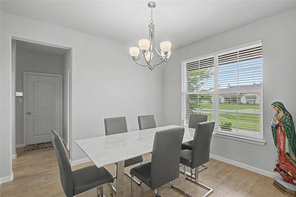 185 Chester Road, Springtown, TX 76082 Dining area featuring wood-finish flooring, a contemporary chandelier, and a large window with blinds