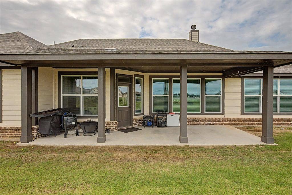 185 Chester Road, Springtown, TX 76082 Covered concrete patio with dark wood-finish support columns and a gray shingle roof