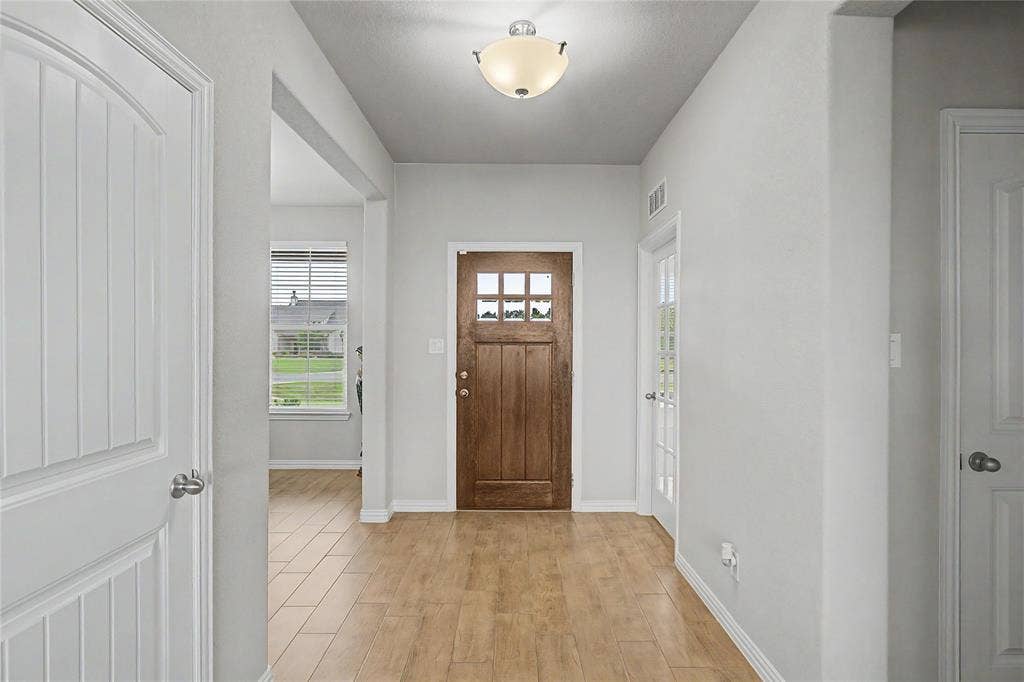 185 Chester Road, Springtown, TX 76082 Entryway featuring wood-finish flooring, a six-paneled wood entry door, and a semi-flush mount ceiling light