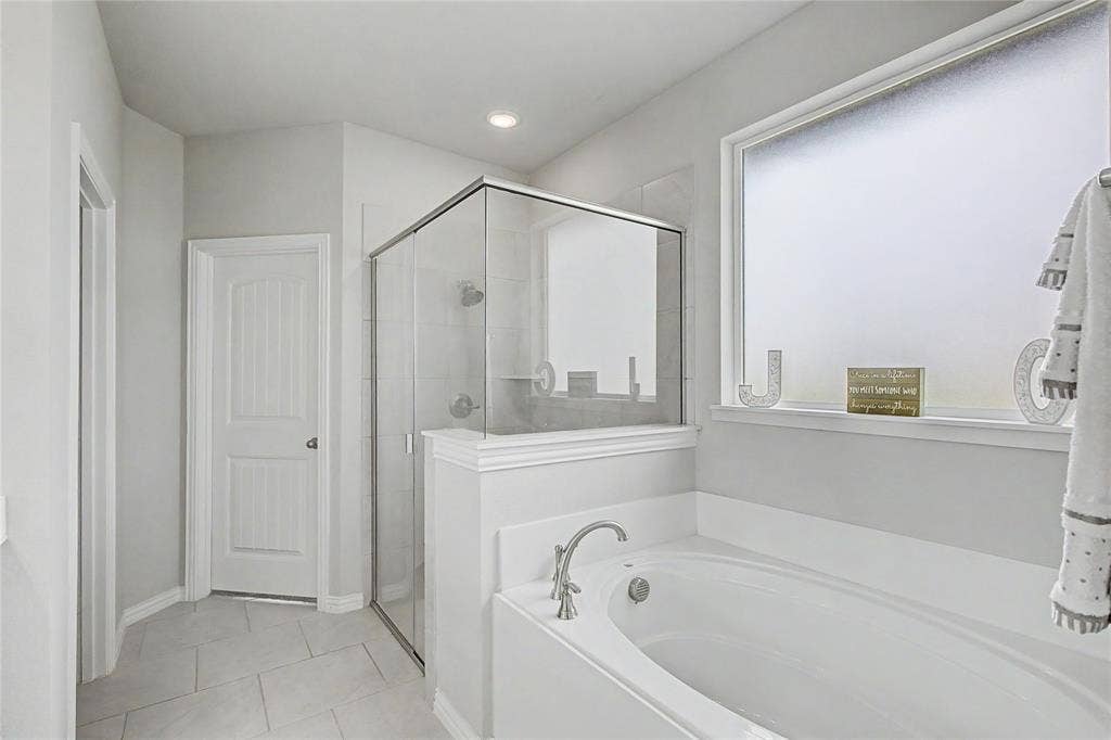 185 Chester Road, Springtown, TX 76082 Bathroom featuring a standalone soaking tub with brushed nickel fixtures, a glass-enclosed shower, a frosted privacy window, and tile flooring