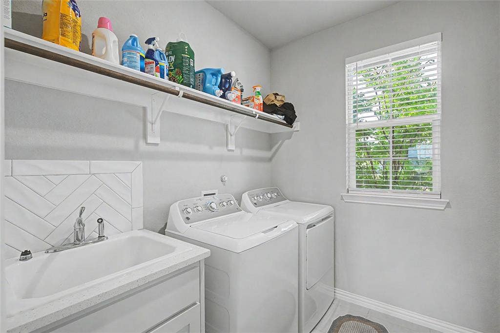 185 Chester Road, Springtown, TX 76082 Laundry room featuring a utility sink with a stone-finish countertop, herringbone tile backsplash, open shelving, and a window for natural light