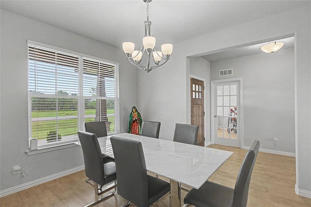 185 Chester Road, Springtown, TX 76082 Dining area featuring wood-finish flooring, a large window with horizontal blinds, and a contemporary chandelier