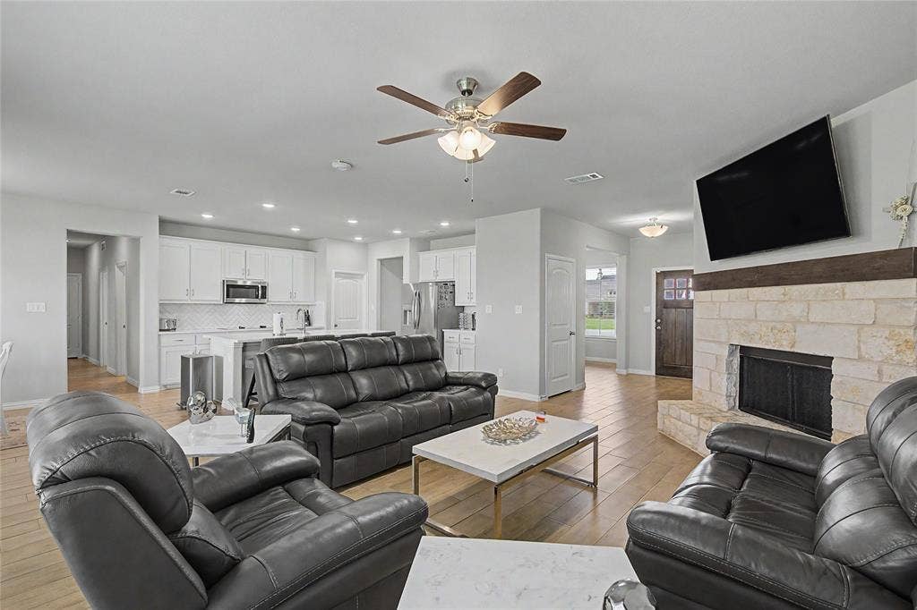 185 Chester Road, Springtown, TX 76082 Open-concept living space featuring wood-finish flooring, a stone fireplace with a wood mantle, and a ceiling fan