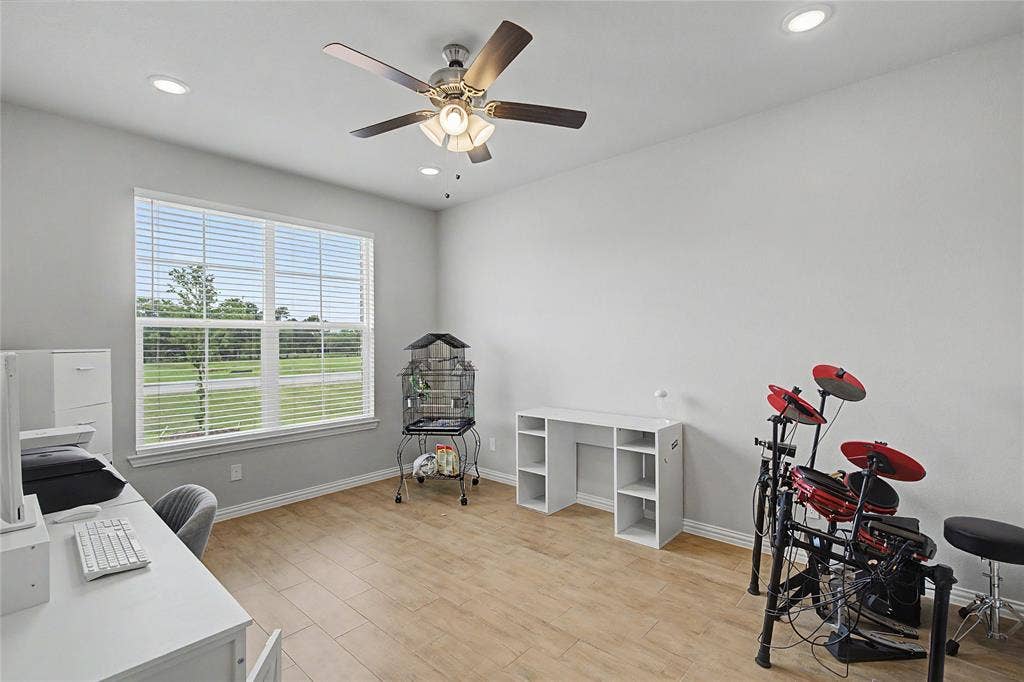 185 Chester Road, Springtown, TX 76082 Spacious room featuring wood-finish flooring, a large window with horizontal blinds, and a ceiling fan with integrated lighting