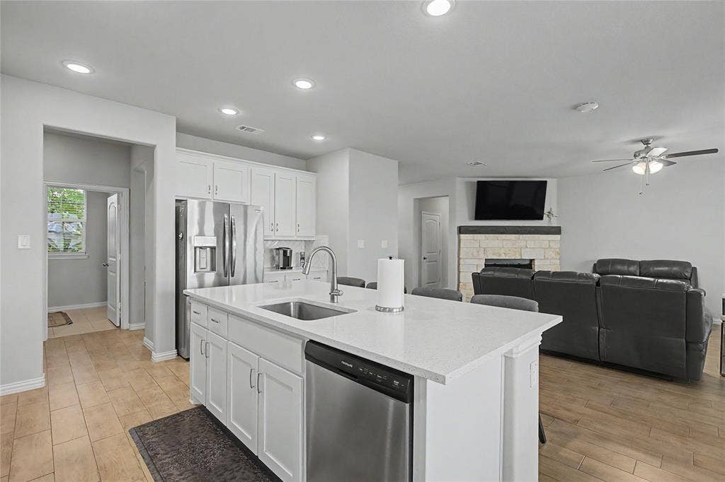 185 Chester Road, Springtown, TX 76082 Open-concept kitchen featuring white cabinetry, stainless steel appliances, a center island with sink, and light-toned countertops