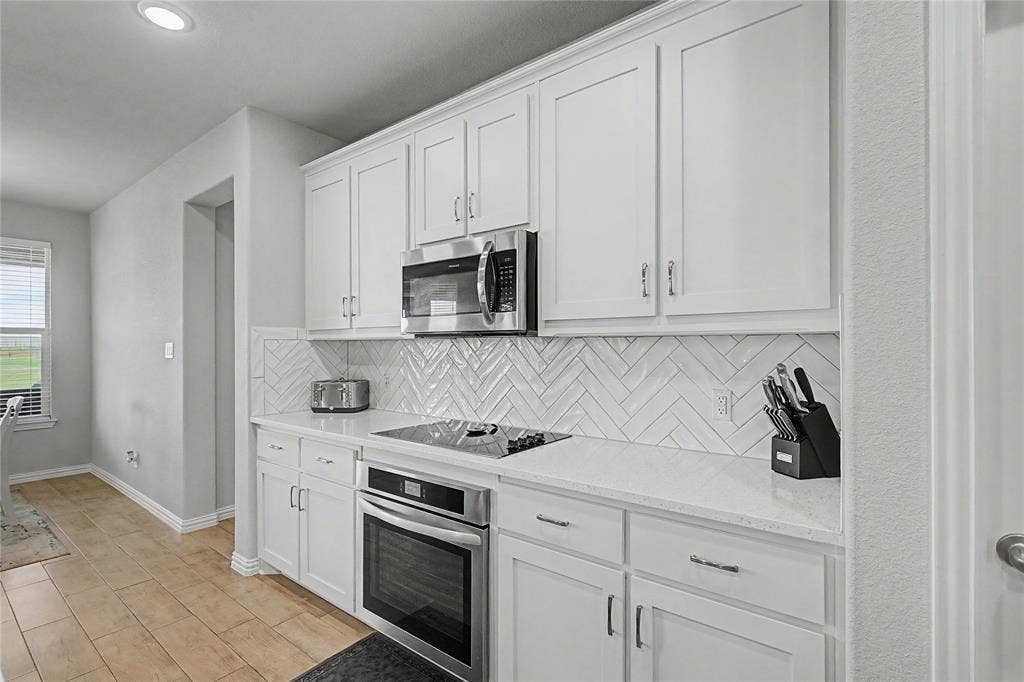 185 Chester Road, Springtown, TX 76082 Bright kitchen featuring white shaker cabinetry, stainless steel microwave, and an integrated oven