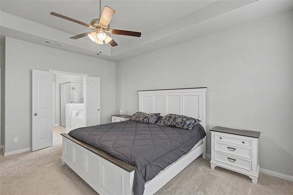 185 Chester Road, Springtown, TX 76082 Carpeted bedroom featuring a tray ceiling with a ceiling fan, light gray wall paint, and white trim
