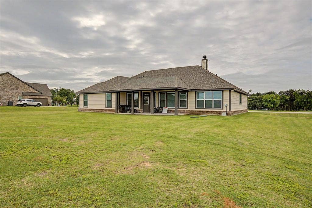 185 Chester Road, Springtown, TX 76082 Expansive green lawn surrounds a single-story residence with a covered patio
