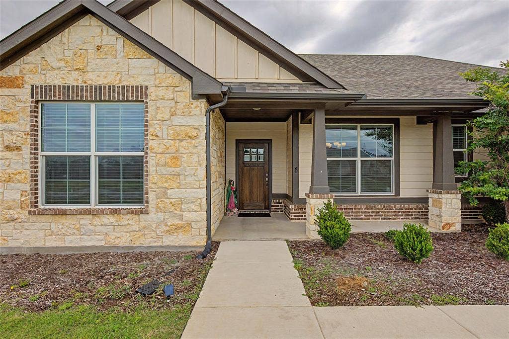 185 Chester Road, Springtown, TX 76082 Crafted stone and brick exterior featuring a covered entry, decorative gables, a wood-finish entry door with glass inserts, and a concrete pathway