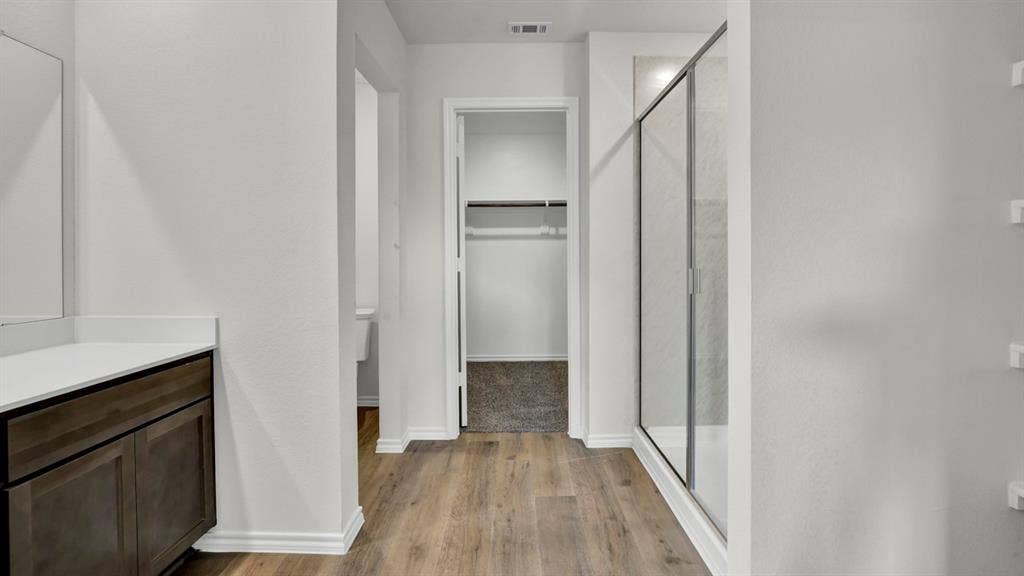 200 Bandit Trail, Terrell, TX 75160 Bathroom with wood-finish flooring, a contemporary vanity with a white countertop, and a glass-enclosed shower