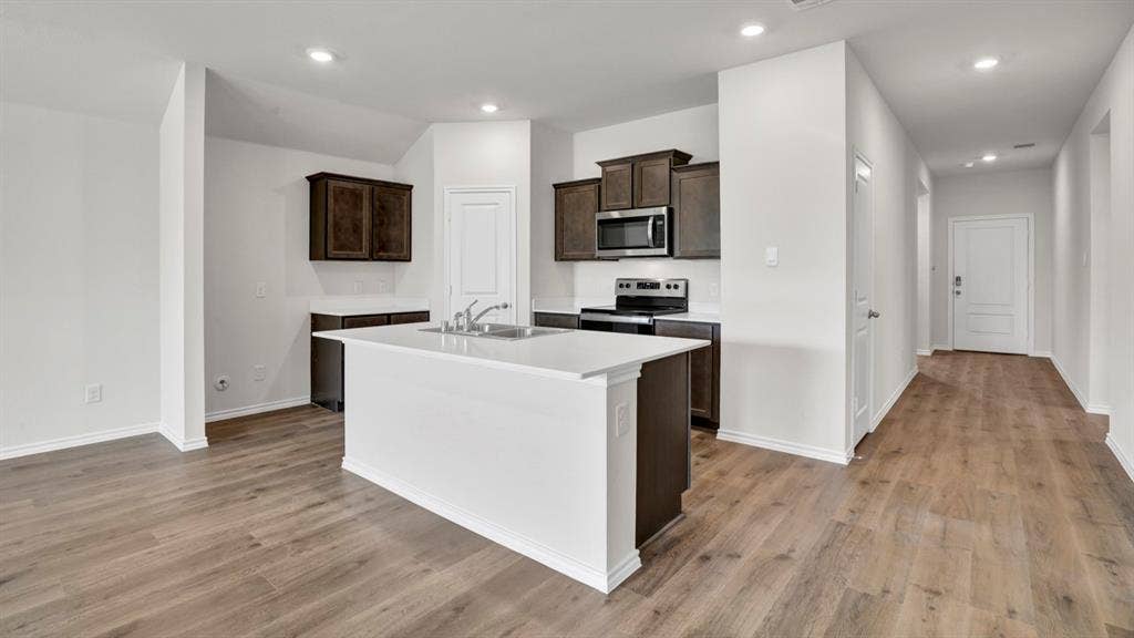 200 Bandit Trail, Terrell, TX 75160 Contemporary kitchen featuring a central island with an undermount sink, dark wood cabinetry, stainless steel appliances, recessed lighting, and wood-finish flooring