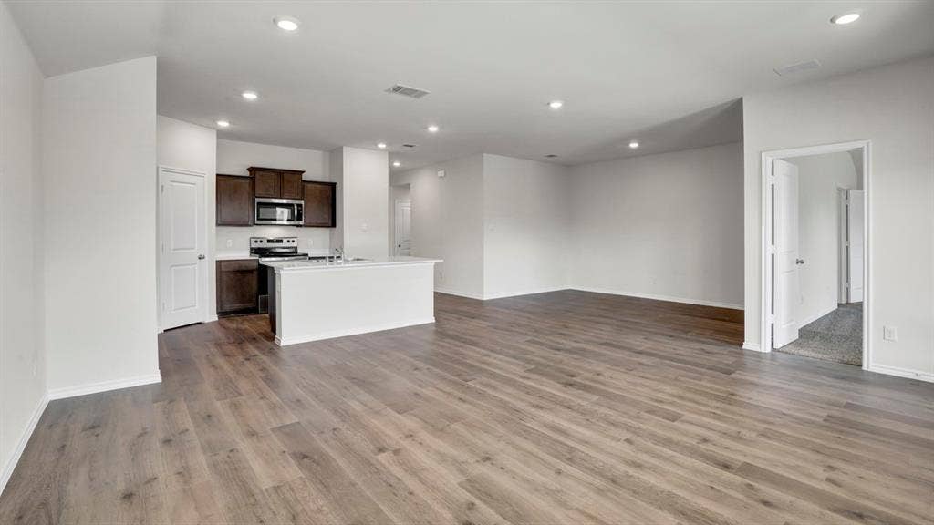 200 Bandit Trail, Terrell, TX 75160 Expansive open-concept living area featuring wood-finish flooring, recessed lighting, and a kitchen with dark wood cabinetry