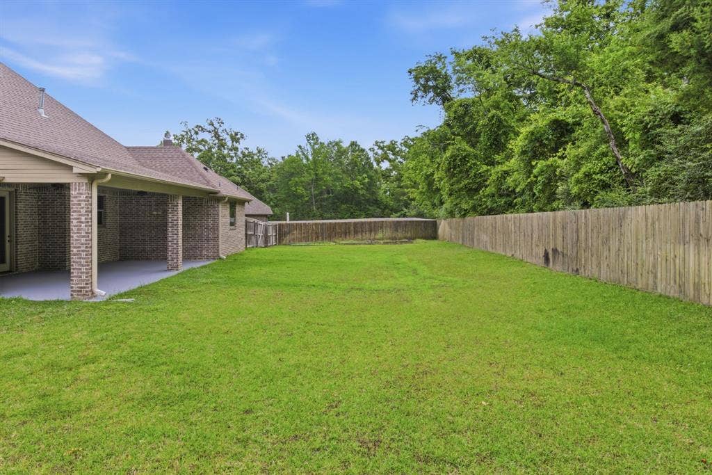 7765 Hickory Spring Lane, Tyler, TX 75703 Expansive green lawn with a wood privacy fence