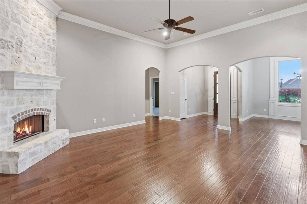 7765 Hickory Spring Lane, Tyler, TX 75703 Spacious living area featuring a stone fireplace with a white mantel, wood-finish flooring, recessed lighting, and multiple arched doorways