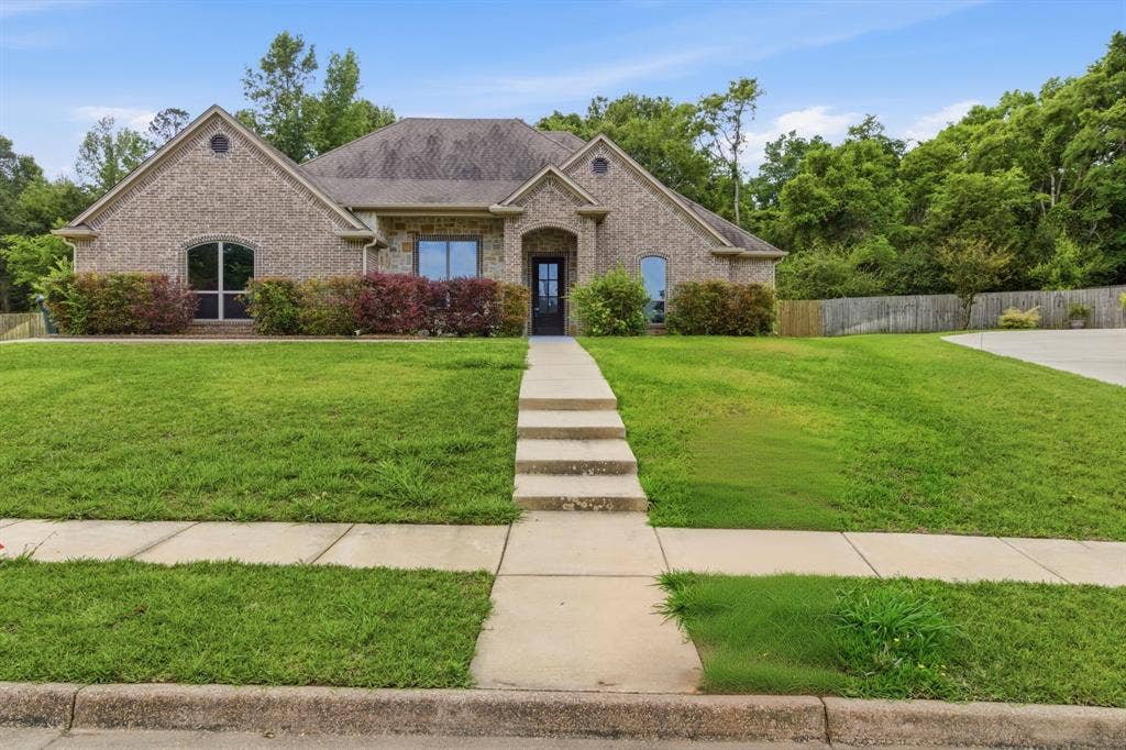 7765 Hickory Spring Lane, Tyler, TX 75703 Brick exterior with gabled roofline, arched windows, and a multi-level concrete walkway