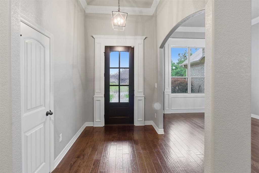 7765 Hickory Spring Lane, Tyler, TX 75703 Entryway featuring dark wood-finish flooring, a glass-paned front door, white trim, a decorative ceiling light fixture, and an arched doorway