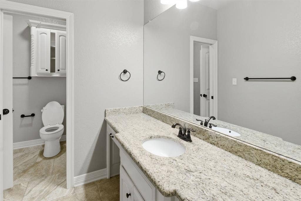 7765 Hickory Spring Lane, Tyler, TX 75703 Spacious vanity featuring a light speckled countertop, undermount sink, and dark bronze fixtures