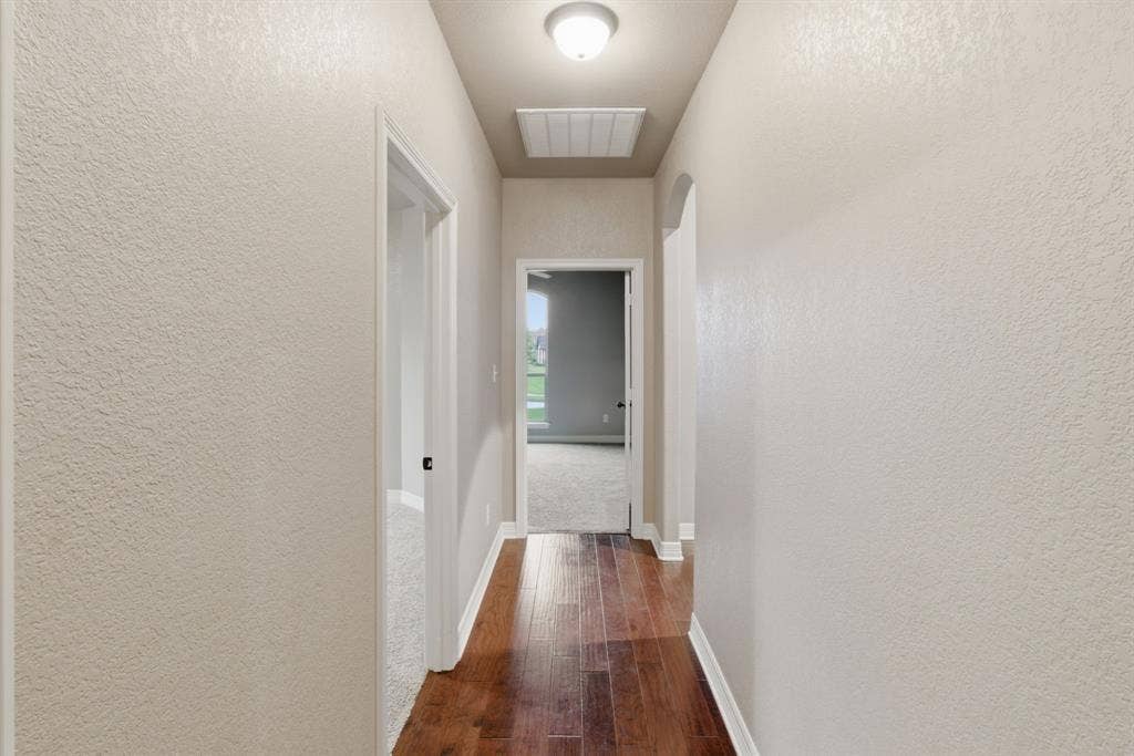 7765 Hickory Spring Lane, Tyler, TX 75703 Central hallway featuring wood-finish flooring, light-toned textured walls, recessed ceiling light, and an attic access panel