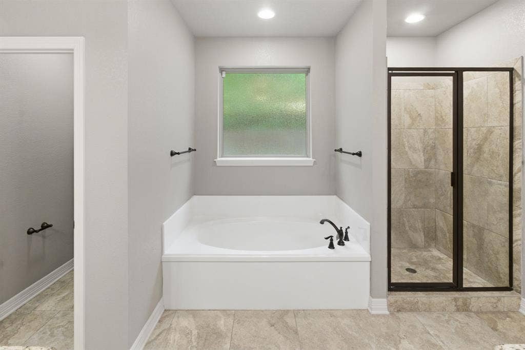 7765 Hickory Spring Lane, Tyler, TX 75703 Recessed soaking tub with matte black fixtures, framed by a frosted window
