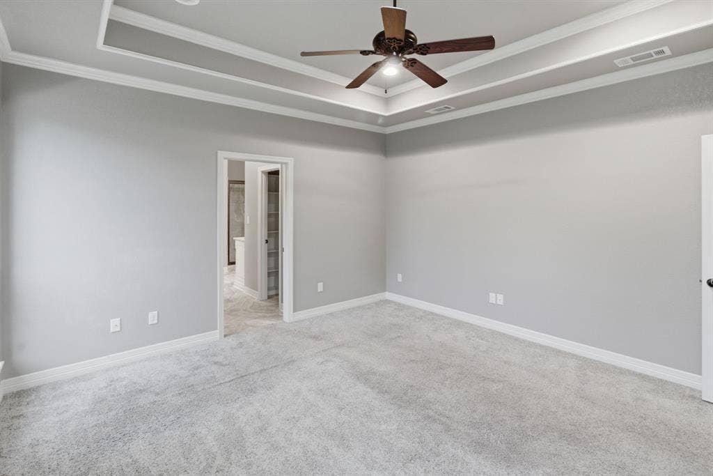 7765 Hickory Spring Lane, Tyler, TX 75703 Spacious room featuring light gray walls, light gray carpet flooring, and a tray ceiling with crown molding