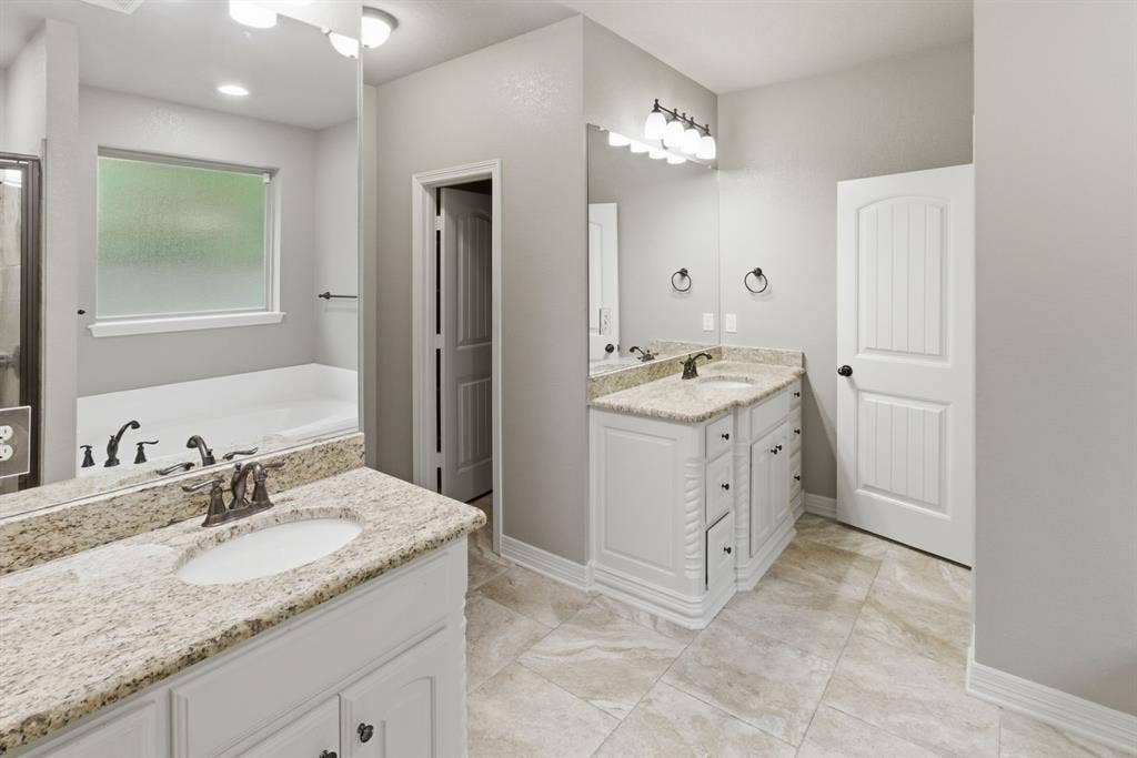 7765 Hickory Spring Lane, Tyler, TX 75703 Spacious bathroom featuring dual vanities with granite countertops, white cabinetry, and undermount sinks