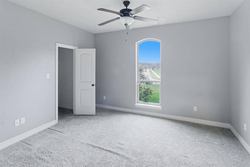 7765 Hickory Spring Lane, Tyler, TX 75703 Carpeted room featuring light gray walls, a ceiling fan with light fixture, and an arched window